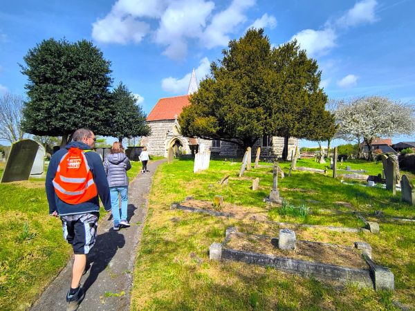 Walking group walk through a graveyard towards a church